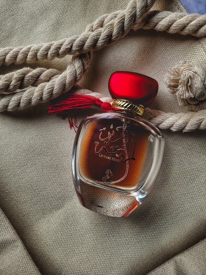 Luxurious perfume bottle with red cap on textured fabric, creating a chic and elegant vibe.