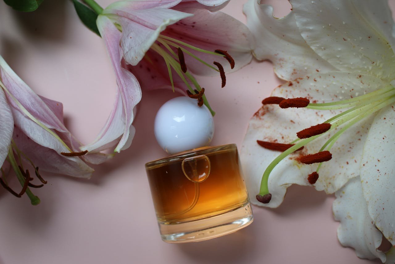 A close-up of a stylish perfume bottle surrounded by pink lilies on a soft background.