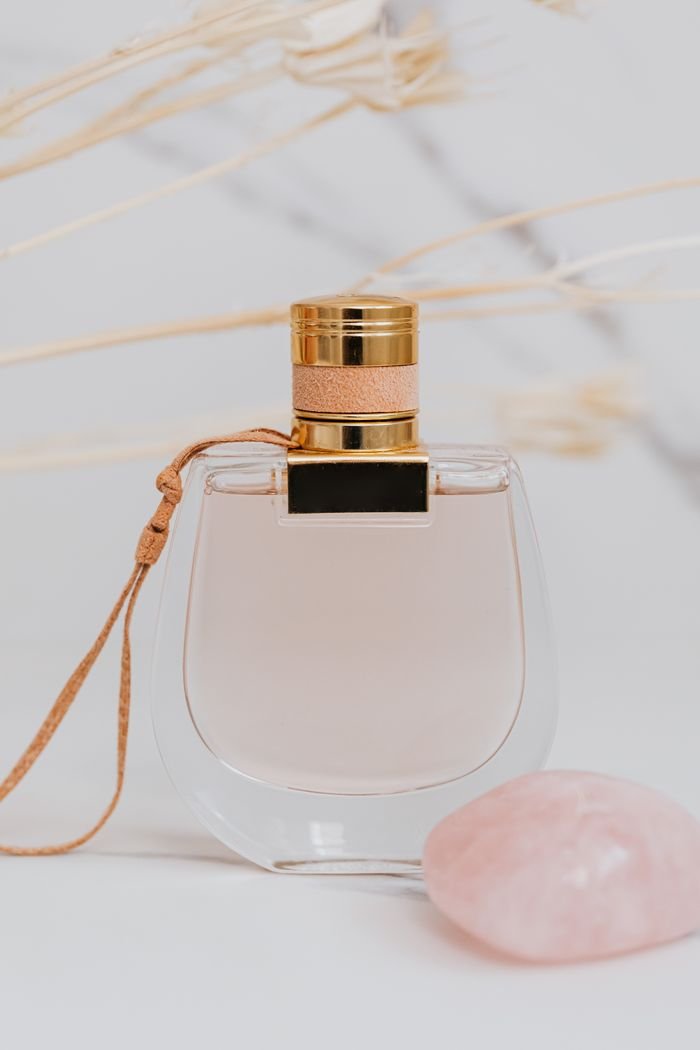 Sophisticated glass perfume bottle with pink stone accents on a minimalistic background.